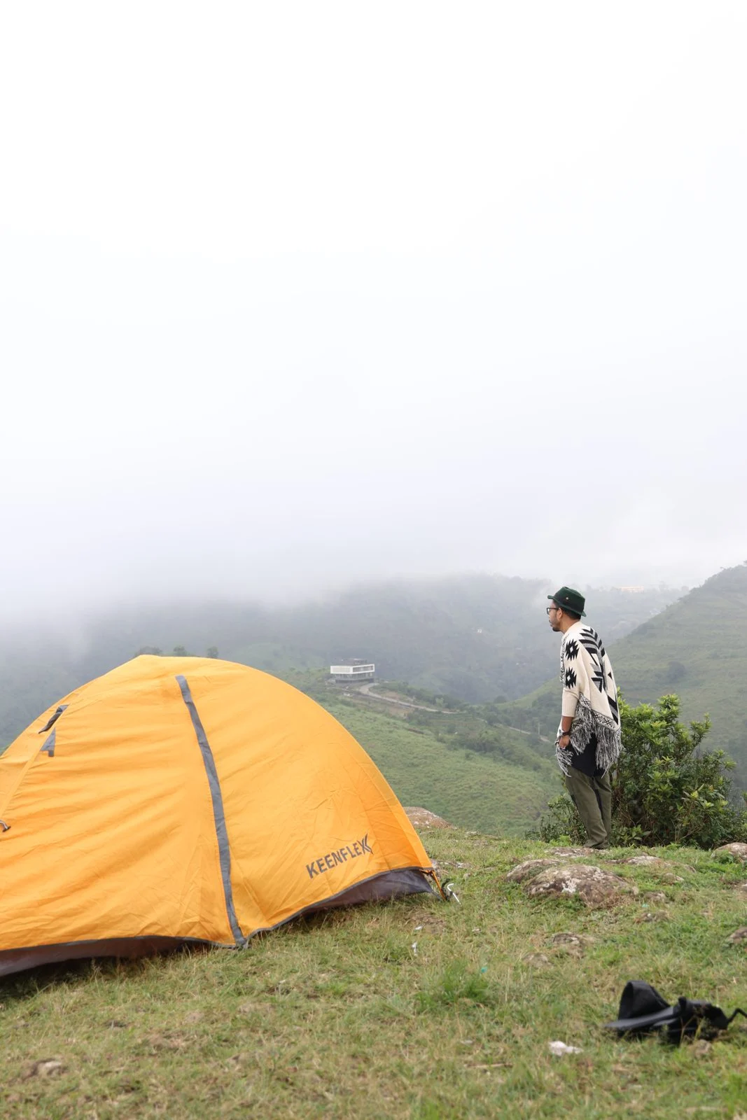 A NeoSkill learner standing beside a tent on a misty hilltop