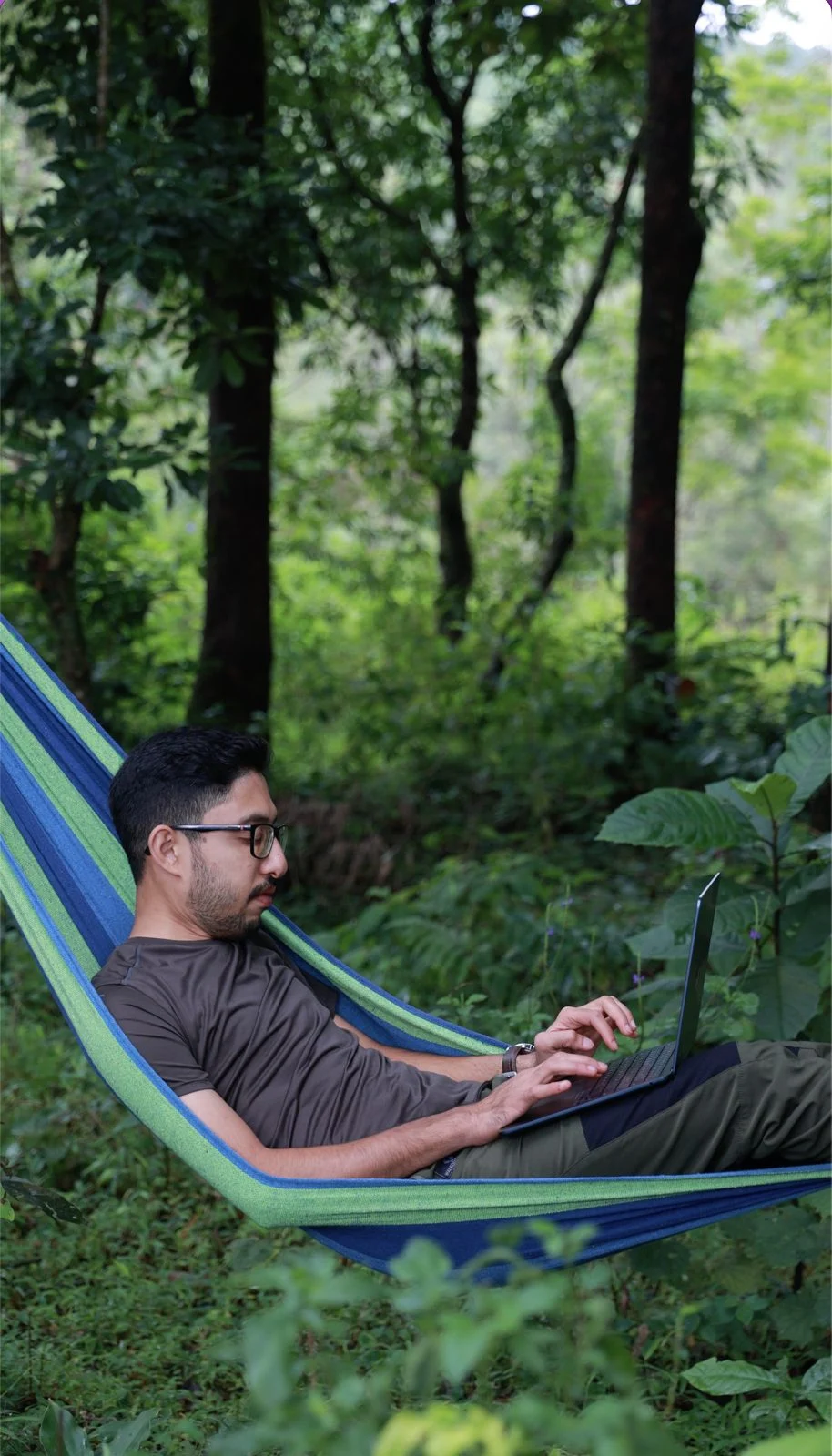 A NeoSkill student working on a laptop in a hammock among trees